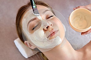 ace peeling mask, spa beauty treatment, skincare. Woman getting facial care by beautician at spa salon, close-up