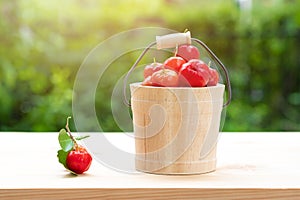 Acerola cherry in wooden bucket on wooden background. Select  focus, Barbados cherry, Malpighia emarginata, high vitamin . Acerola