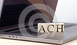 ACH word on wooden block on laptop, business concept photo