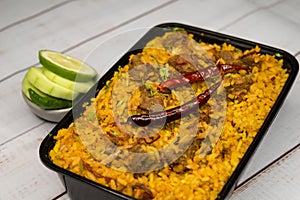 Achari beef khichuri biryani rice pulao with cucumber and lemon slice served in dish isolated on wooden table side view of