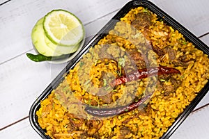 Achari beef khichuri biryani rice pulao with cucumber and lemon slice served in dish isolated on wooden table top view closeup of