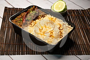 Achari beef pulao biryani rice with cucumber and lemon slice served in dish isolated on wooden table side view of bangladeshi and