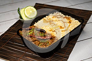 Achari beef pulao biryani rice with cucumber and lemon slice served in dish isolated on wooden table side view of bangladeshi and