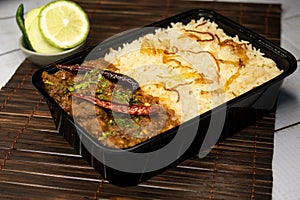 Achari beef pulao biryani rice with cucumber and lemon slice served in dish isolated on wooden table side view closeup of