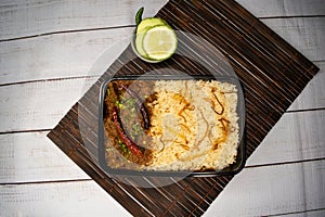 Achari beef pulao biryani rice with cucumber and lemon slice served in dish isolated on wooden table top view closeup of