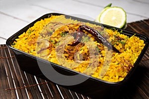 Achari chicken khichuri biryani rice pulao with cucumber and lemon slice served in dish isolated on wooden table side view of