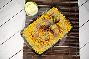 Achari chicken khichuri biryani rice pulao with cucumber and lemon slice served in dish isolated on wooden table top view closeup