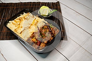 Achari chicken pulao biryani rice with cucumber and lemon slice served in dish isolated on wooden table side view closeup of