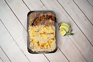 Achari chicken pulao biryani rice with cucumber and lemon slice served in dish isolated on wooden table top view of bangladeshi