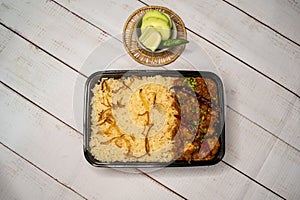 Achari chicken pulao biryani rice with cucumber and lemon slice served in dish isolated on wooden table top view of bangladeshi
