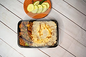Achari chicken pulao biryani rice with cucumber and lemon slice served in dish isolated on wooden table top view closeup of
