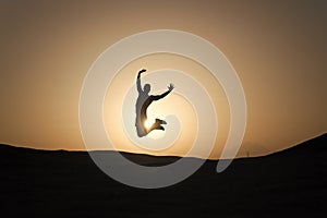 Achieve main goal. Silhouette man motion jump in front of sunset sky background. Future success depends on your efforts