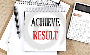ACHIEVE RESULTS is written in white notepad near a calculator, clipboard and pen. Business concept