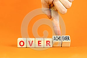 Achiever or overachiever symbol. Businessman turns wooden cubes and changes word Achiever to Overachiever. Beautiful orange