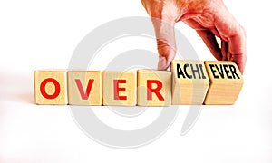 Achiever or overachiever symbol. Businessman turns wooden cubes and changes word Achiever to Overachiever. Beautiful white