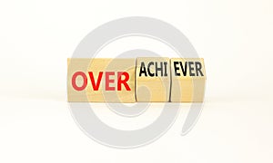 Achiever or overachiever symbol. Businessman turns wooden cubes and changes word Achiever to Overachiever. Beautiful white