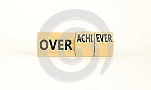 Achiever or overachiever symbol. Businessman turns wooden cubes and changes word Achiever to Overachiever. Beautiful white