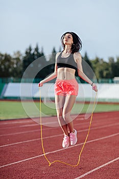 Achieving best results. Beautiful young brunette woman in sports clothing skipping rope and smiling while exercising on the