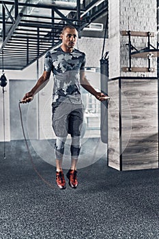 Achieving best results. Full length of young African man in sport clothing skipping rope while exercising in the gym
