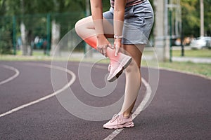 Achilles tendon injury, callus on the heel while running, foot pain, woman suffering from feet ache on a sports ground, podiatry