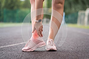 Achilles tendon injury, callus on the heel while running, foot pain, woman suffering from feet ache on a sports ground, podiatry