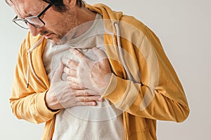 Aching chest, adult male with painful grimace pressing the upper abdomen with his hands to ease pain