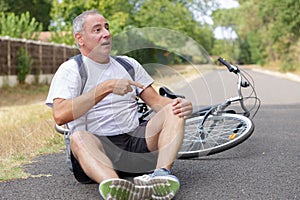 Aching man after bicycle accident on asphalt