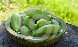 Achocha, Cyclanthera pedata healthy vegetables in wooden bowl on wooden log. Green nature background.