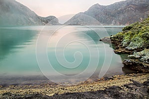 Acid lake in the crater of Mount Ijen, East Java, Indonesia. Calm turquiose water; sulfurous deposits on shoreline.