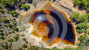 Acidic red lake in place of abandoned open pit copper mine near Kinousa, Cyprus, aerial view directly above