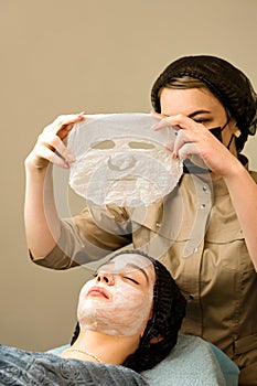 Acne treatment at beautician. Applying sheet mask