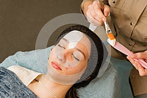 Acne treatment at doctor. Applying facial mask