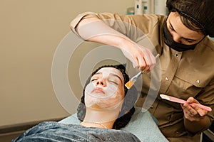 Acne treatment at doctor. Applying facial mask