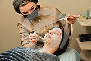 Acne treatment at doctor. Applying facial mask