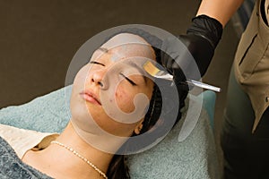 Acne treatment at doctor. Applying facial mask