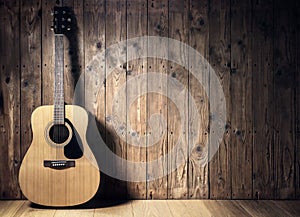 Acoustic guitar against blank wooden plank panel grunge background with copy space