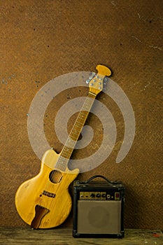 Acoustic guitar and amplifier resting against old steel background with copy space