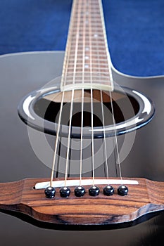 Acoustic guitar with black top with six strings closeup