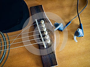 Acoustic guitar with broken guitar strings and earphone
