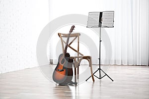 Acoustic guitar, chair and note stand with music sheets