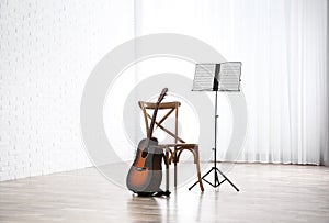 Acoustic guitar, chair and note stand with music sheets