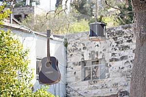 Acoustic guitar and drum hanging on a tree with houses on the background