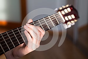 Acoustic guitar fretboard with Caucasian female long fingers hand striking a chord