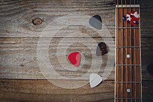 An acoustic guitar fretboard and some guitar picks on wooden table