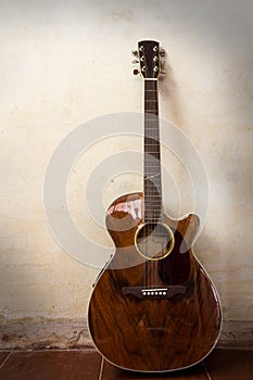 Acoustic guitar with grunge texture wall.