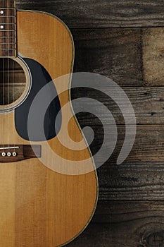 An acoustic guitar on grunge wood background to use as book cover for a guitar course