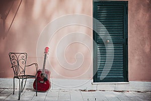 acoustic guitar lying in front of the house with empty chair, vintage style with copy space photo