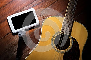 Acoustic guitar with microphone and computer tablet.