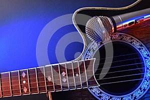 Acoustic guitar and microphone isolated with red and blue lights