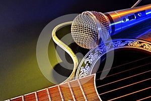 Acoustic guitar and microphone isolated with yellow and blue lights